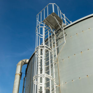 Escalera de crinolina metálica para acceso seguro en instalaciones industriales.