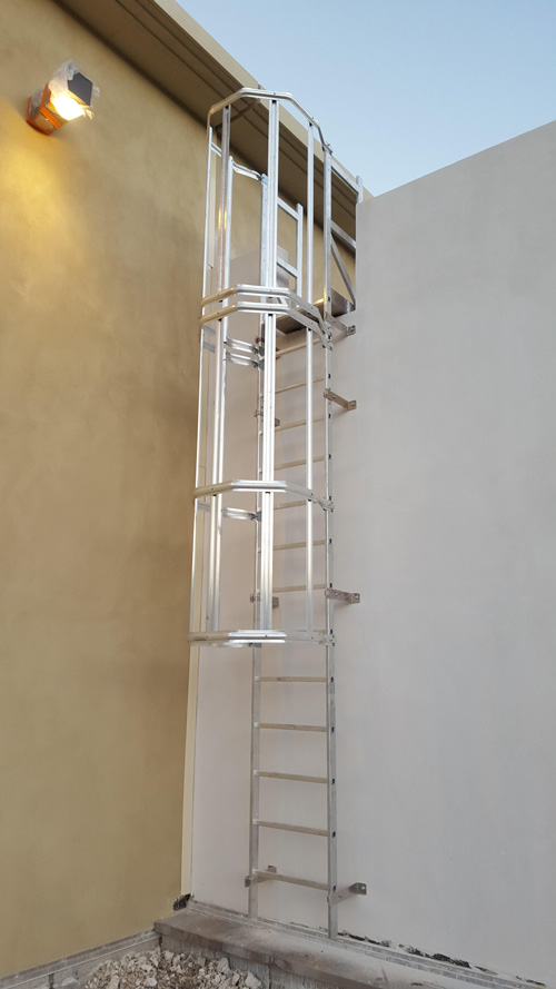 Escalera de crinolina metálica para acceso seguro en instalaciones industriales.
