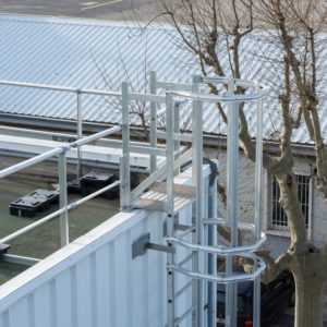 Escalera de crinolina metálica para acceso seguro en instalaciones industriales.