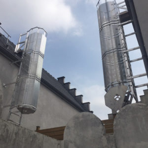 Escalera de crinolina metálica para acceso seguro en instalaciones industriales.
